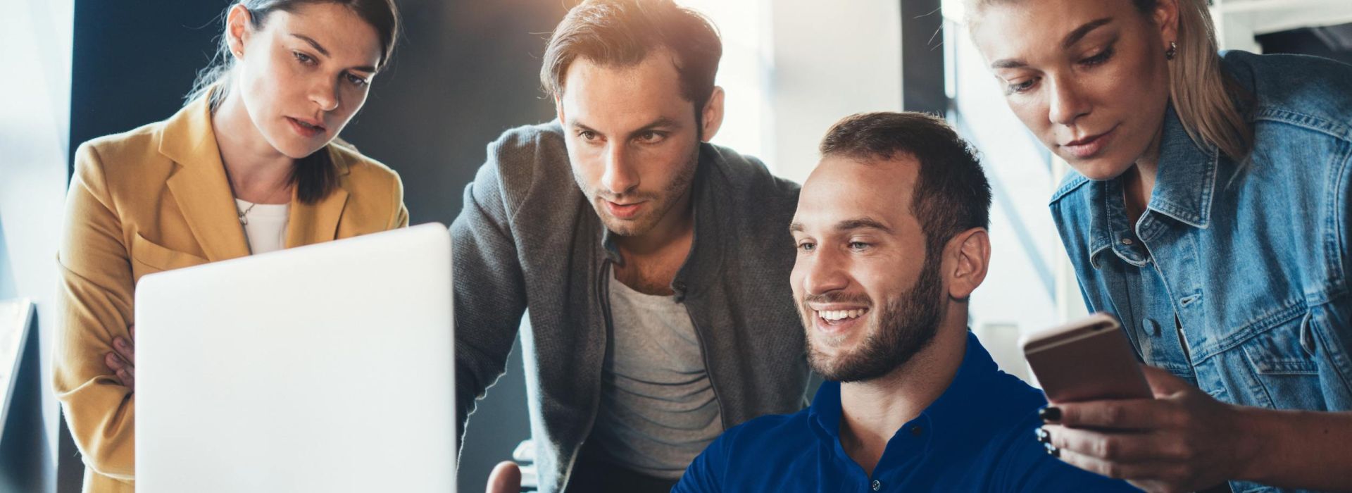 Ein Team schaut während eines Business Meetings auf einen Laptop.