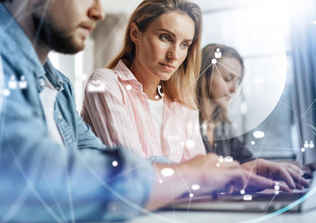 Zwei Frauen und ein Mann arbeiten an einem Notebook.